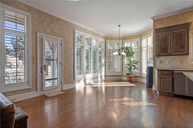 interior space featuring dark hardwood / wood-style flooring, ornamental molding, plenty of natural light, and a chandelier