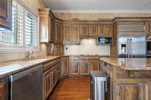 kitchen with sink, crown molding, backsplash, dark hardwood / wood-style floors, and built in appliances