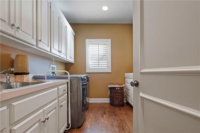 clothes washing area with separate washer and dryer, sink, dark hardwood / wood-style floors, and cabinets