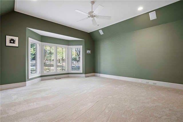 spare room with vaulted ceiling, light colored carpet, and ceiling fan