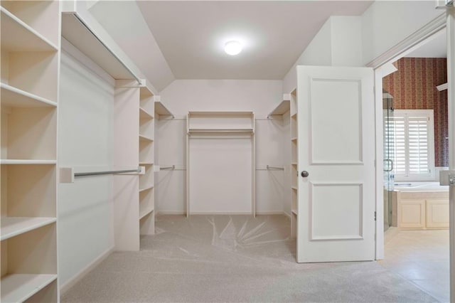 spacious closet with lofted ceiling and light carpet