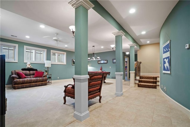 carpeted living room featuring ceiling fan, ornamental molding, and decorative columns