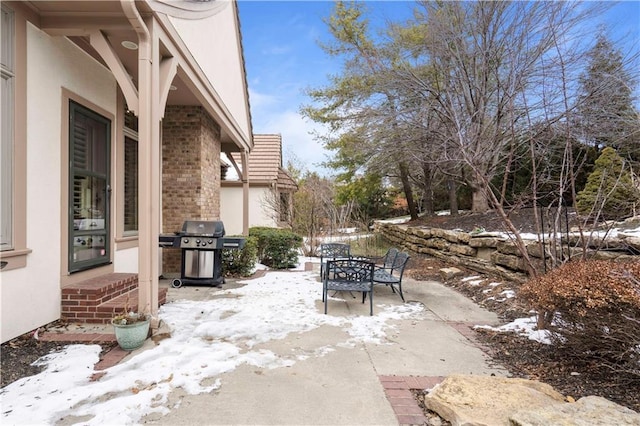 snow covered patio featuring a grill