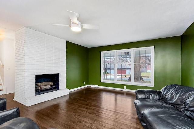 living room featuring ceiling fan, dark hardwood / wood-style flooring, and a fireplace