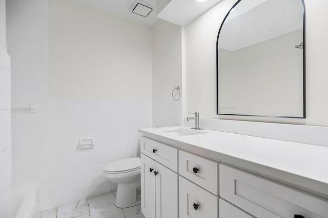 bathroom with vanity, tile walls, and toilet