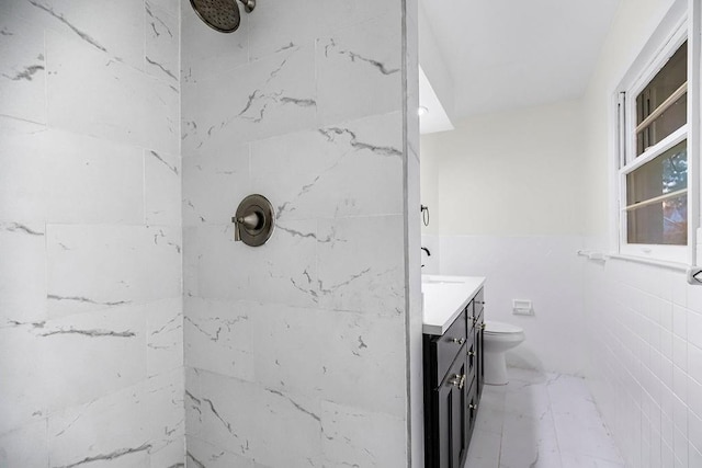 bathroom with a tile shower, vanity, and toilet