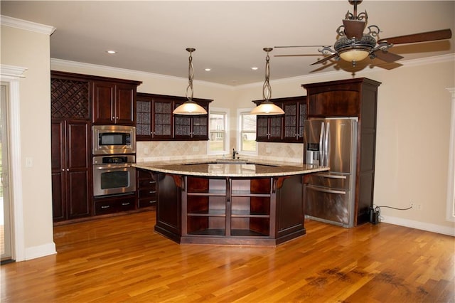 kitchen featuring appliances with stainless steel finishes, decorative light fixtures, decorative backsplash, a kitchen island, and light wood-type flooring