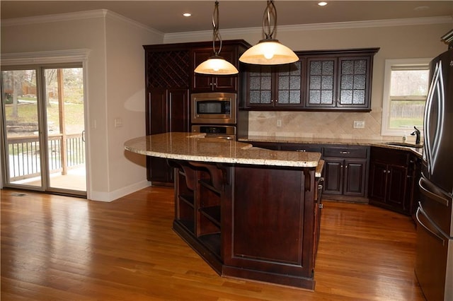 bar with pendant lighting, dark brown cabinets, plenty of natural light, and appliances with stainless steel finishes