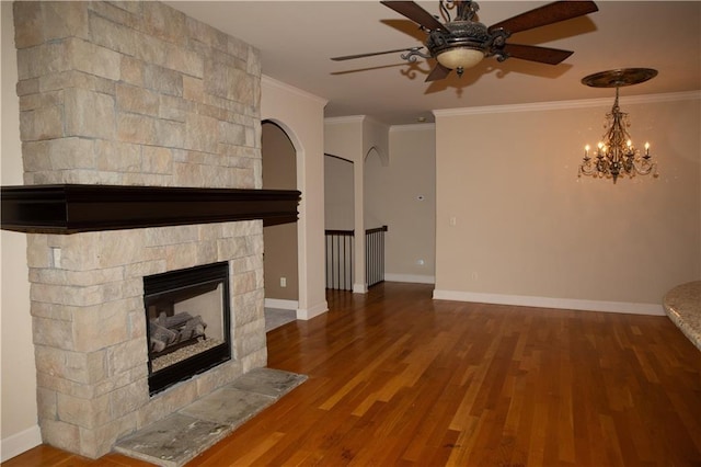 unfurnished living room with hardwood / wood-style floors, ceiling fan with notable chandelier, a stone fireplace, and ornamental molding