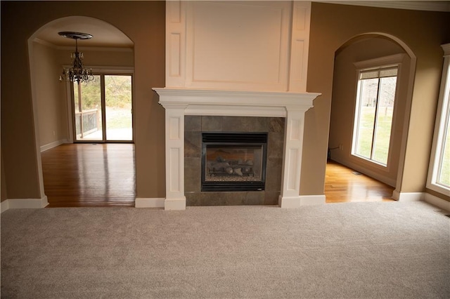 unfurnished living room featuring a tile fireplace, carpet flooring, and a wealth of natural light