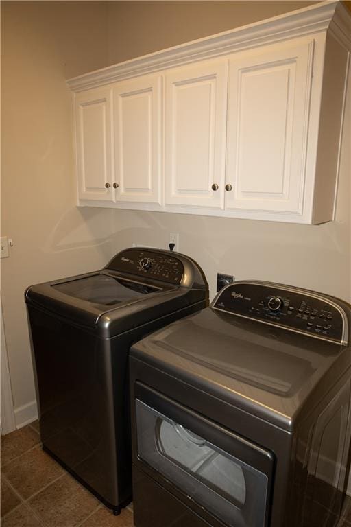 laundry area with washer and dryer, cabinets, and dark tile patterned floors