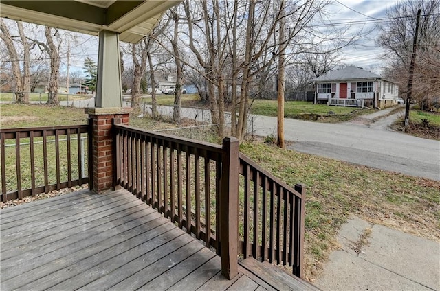 wooden deck featuring covered porch and a lawn