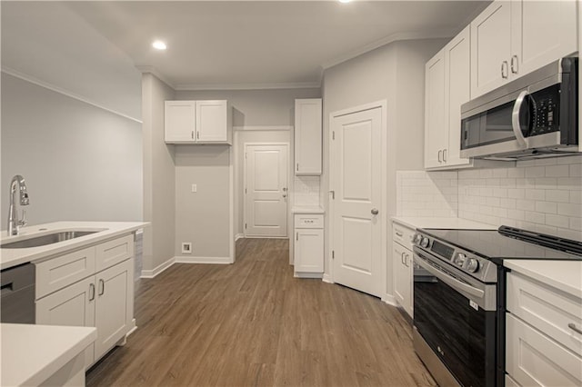 kitchen with backsplash, sink, light hardwood / wood-style flooring, appliances with stainless steel finishes, and white cabinetry