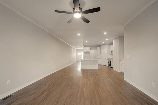 unfurnished living room featuring crown molding, ceiling fan, and dark wood-type flooring