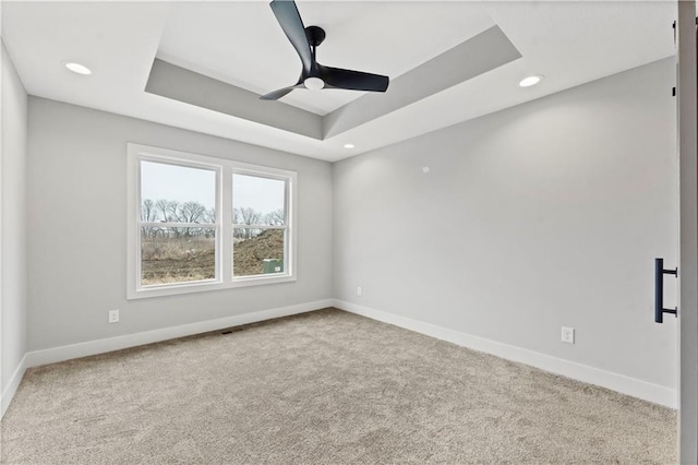 spare room featuring a tray ceiling, ceiling fan, and carpet flooring