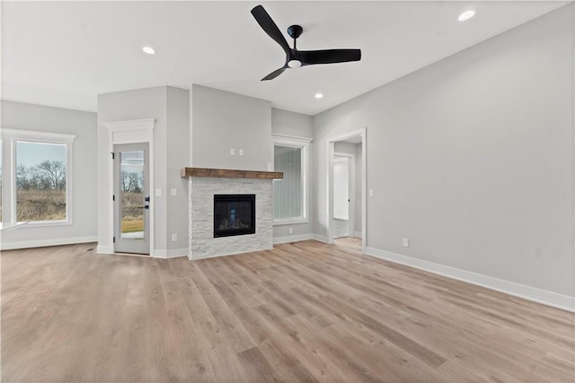 unfurnished living room with ceiling fan, a fireplace, and light hardwood / wood-style flooring