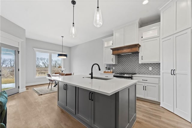 kitchen with pendant lighting, stainless steel range with gas cooktop, sink, and white cabinets