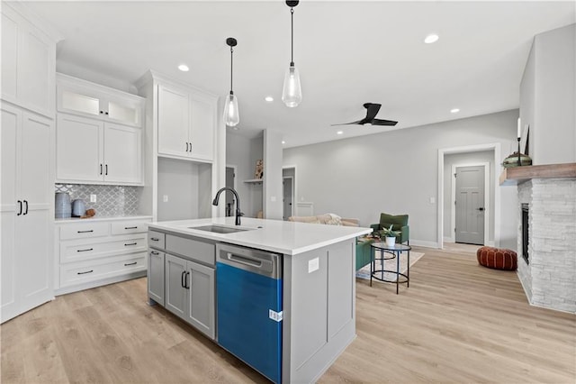 kitchen with white cabinets, sink, dishwasher, and a center island with sink