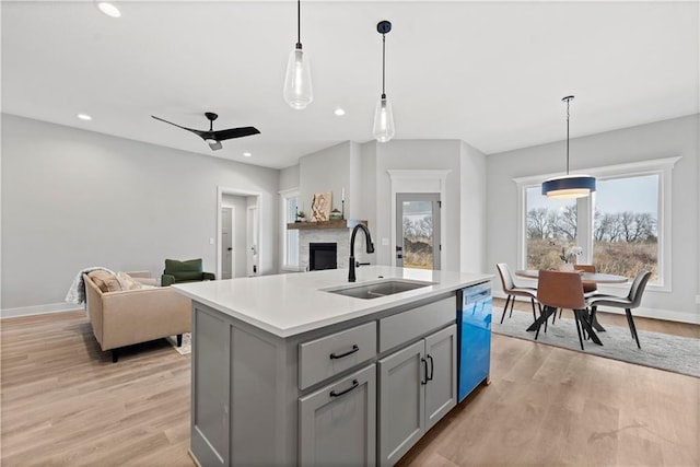 kitchen with pendant lighting, sink, gray cabinetry, an island with sink, and stainless steel dishwasher