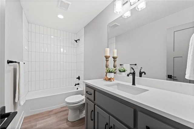 full bathroom with vanity, tiled shower / bath combo, wood-type flooring, and toilet