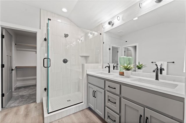 bathroom featuring a shower with door, vaulted ceiling, wood-type flooring, and vanity