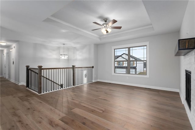 unfurnished living room featuring hardwood / wood-style floors, ceiling fan, and a raised ceiling