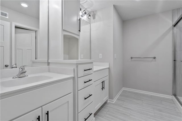 bathroom featuring vanity and a shower with door