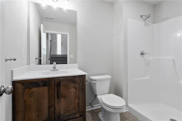 bathroom with tile patterned flooring, vanity, toilet, and a shower