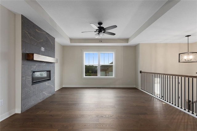 1316 N Holland Ct, Independence, MO 64056 - unfurnished living room with a ceiling fan, a tray ceiling, wood finished floors, a fireplace, and baseboards