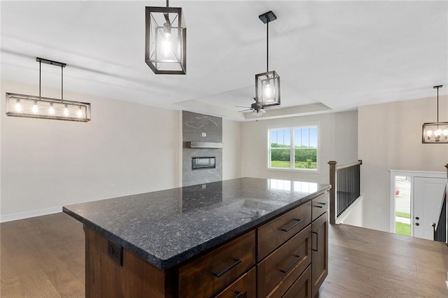 1316 N Holland Ct, Independence, MO 64056 - kitchen with dark wood-style flooring, ceiling fan, a fireplace, hanging light fixtures, and a kitchen island