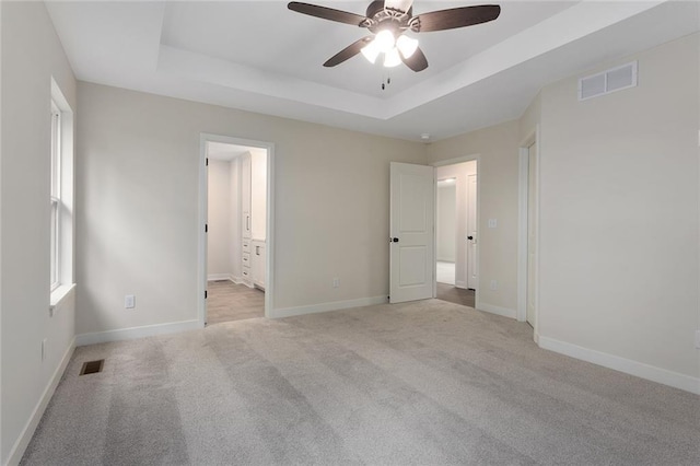 1316 N Holland Ct, Independence, MO 64056 - unfurnished bedroom featuring a tray ceiling, carpet, baseboards, and connected bathroom