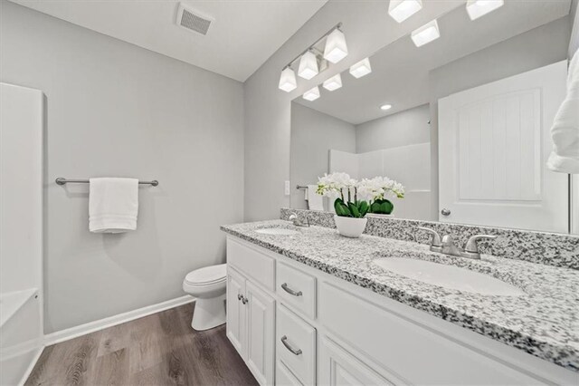 bathroom featuring walk in shower, vanity, wood-type flooring, and toilet