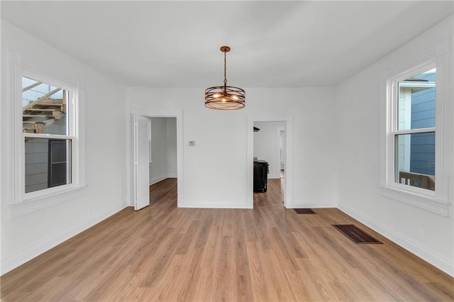 unfurnished dining area with light wood-type flooring and a notable chandelier