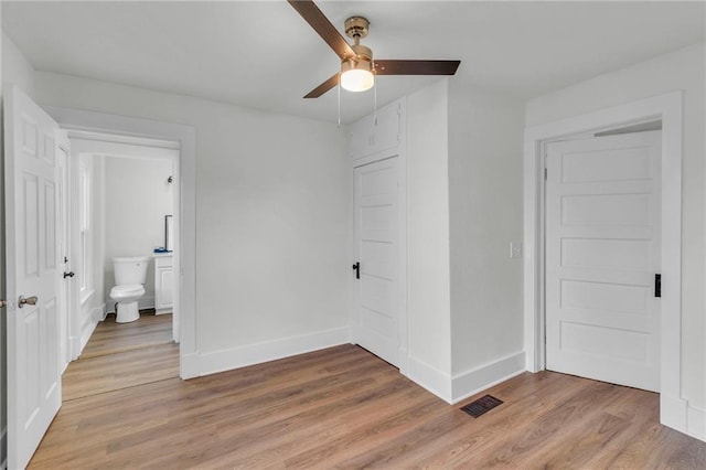 unfurnished bedroom with ensuite bath, ceiling fan, a closet, and light wood-type flooring