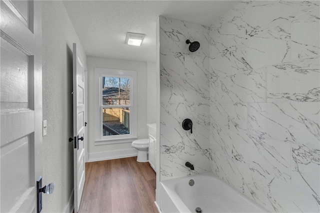 bathroom featuring hardwood / wood-style flooring, toilet, and tiled shower / bath