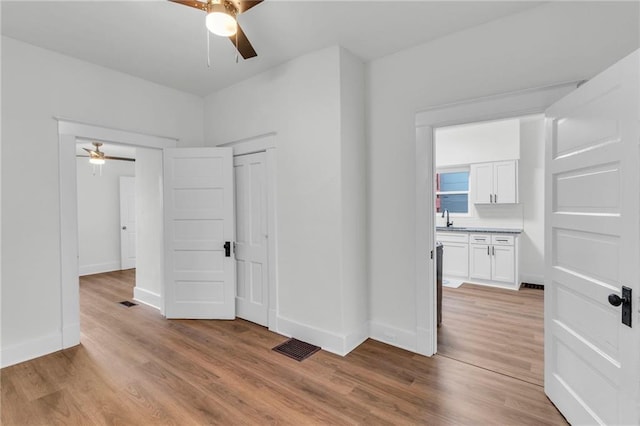 unfurnished bedroom featuring ceiling fan, sink, and light wood-type flooring