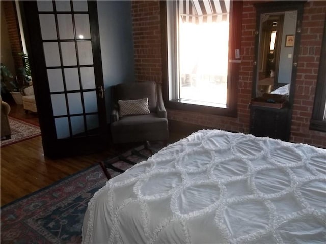 bedroom with wood-type flooring and brick wall