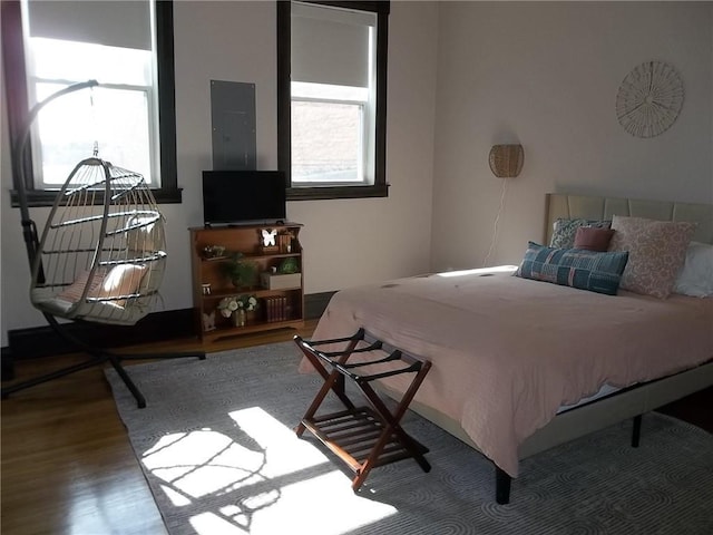 bedroom featuring hardwood / wood-style flooring, electric panel, and multiple windows