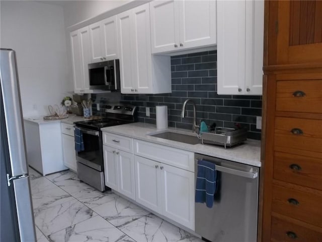 kitchen with sink, white cabinets, backsplash, light stone counters, and stainless steel appliances