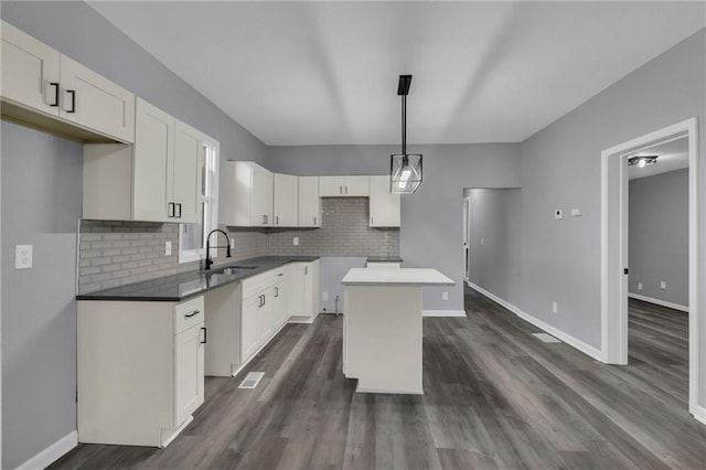 kitchen with white cabinetry, sink, a kitchen island, and pendant lighting