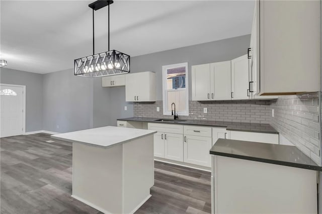 kitchen featuring white cabinetry, a center island, dark hardwood / wood-style floors, backsplash, and decorative light fixtures