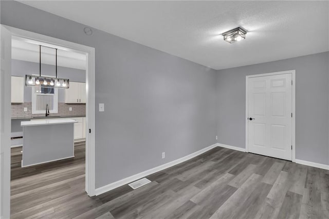 unfurnished room featuring a textured ceiling, dark hardwood / wood-style flooring, and sink