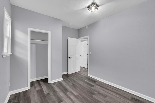 unfurnished bedroom with dark wood-type flooring and a closet