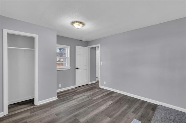 unfurnished bedroom featuring dark hardwood / wood-style floors, a textured ceiling, and a closet