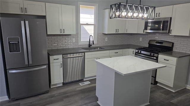 kitchen featuring white cabinets, dark wood-type flooring, a sink, stainless steel appliances, and backsplash