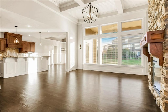 9509 W 164th St, Stilwell, KS 66085 - unfurnished living room featuring dark wood-style flooring, a chandelier, beam ceiling, crown molding, and a fireplace