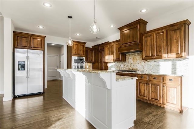 kitchen featuring dark wood-type flooring, hanging light fixtures, decorative backsplash, an island with sink, and appliances with stainless steel finishes