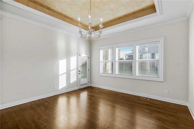 spare room with ornamental molding, an inviting chandelier, a raised ceiling, and dark wood-type flooring