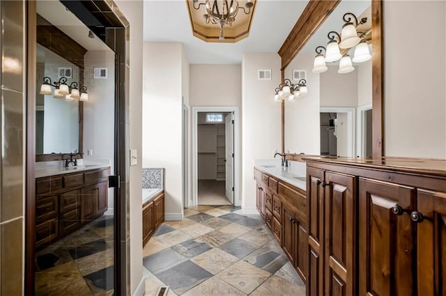 bathroom featuring a chandelier, vanity, and a bathtub