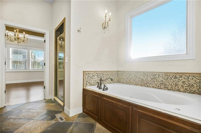 9509 W 164th St, Stilwell, KS 66085 - full bathroom with stone tile flooring, a bath, and a chandelier